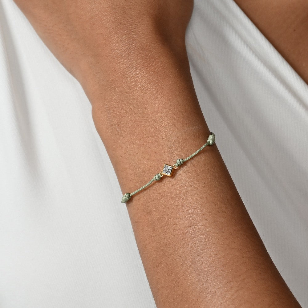 Nahaufnahme von einem grünen Cord-Armband mit einem Labordiamanten im Princessschliff am Arm getragen.