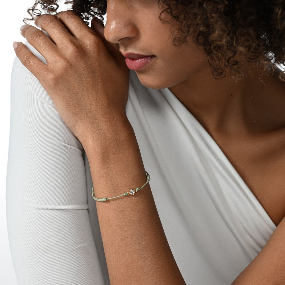 Frau trägt ein grünes Cord-Armband mit einem Labordiamanten im Princessschliff in Zargenfassung.