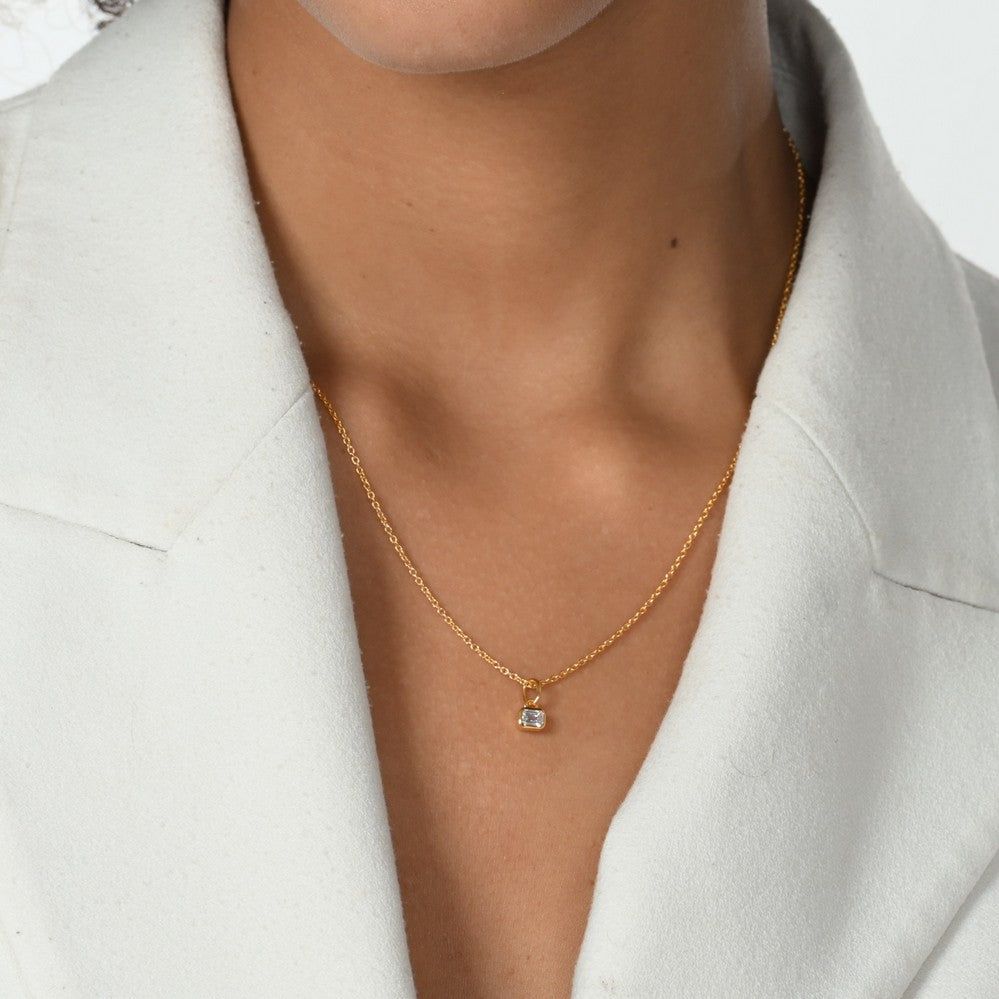 Frau im weißen Blazer trägt eine Halskette mit einem goldenen Anhänger mit Labordiamanten in Oktagonform.