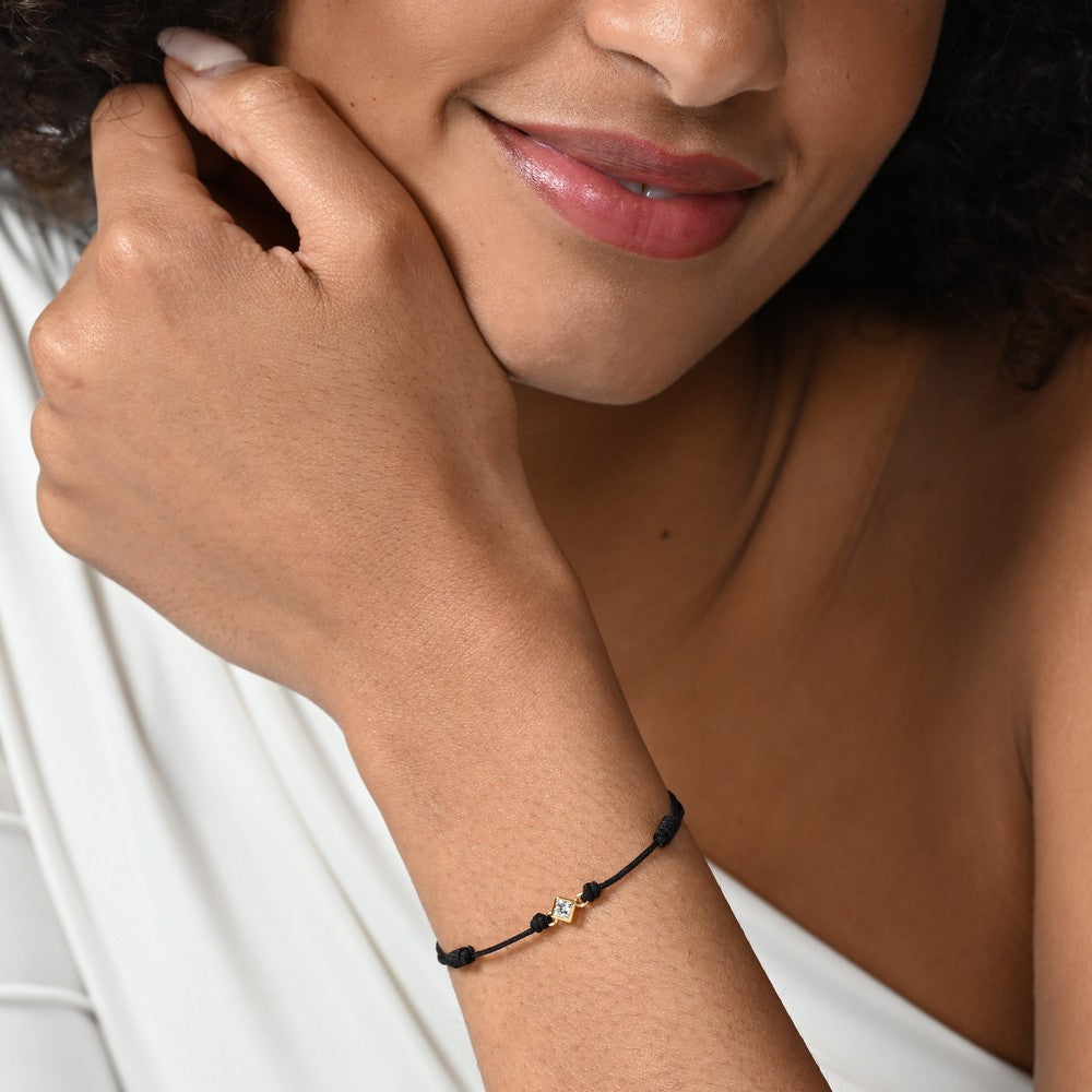 Nahaufnahme von einem schwarzen Cord-Armband mit einem kleinen Labordiamanten im Princessschliff am Arm getragen.