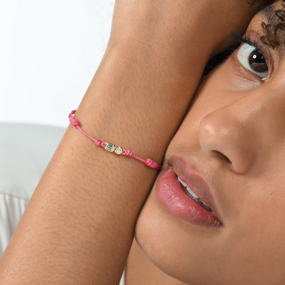 Nahaufnahme von einem pinken Cord-Armband mit 2 großen Labordiamanten im Brillant- und Smaragdschliff am Arm getragen.