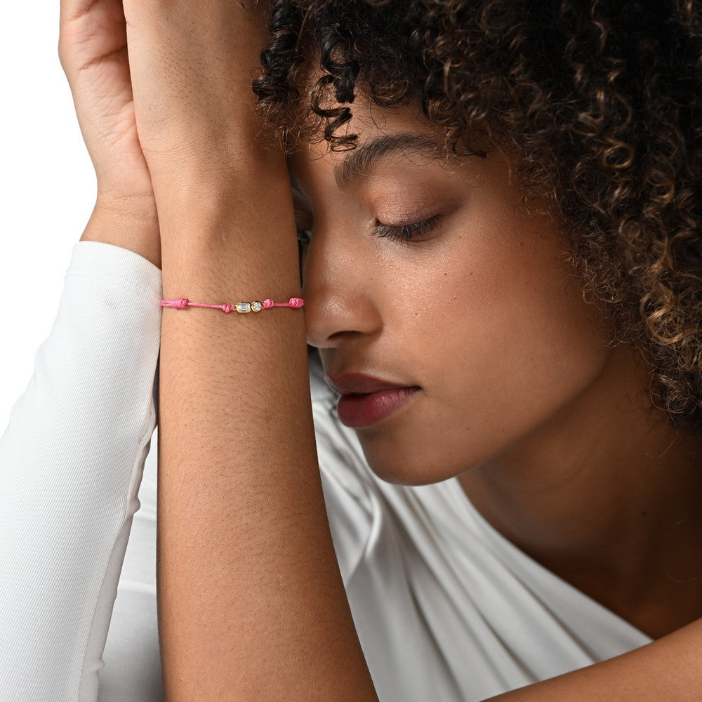 Frau trägt ein pinkes Cord-Armband mit zwei großen Labordiamanten im Brillant- und Smaragdschliff in Zargenfassung.