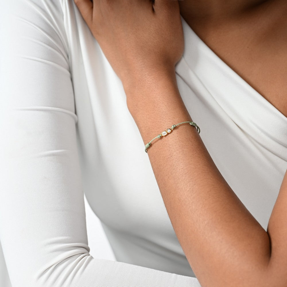 Frau trägt ein grünes Cord-Armband mit zwei großen Labordiamanten im Brillant- und Smaragdschliff in Zargenfassung.