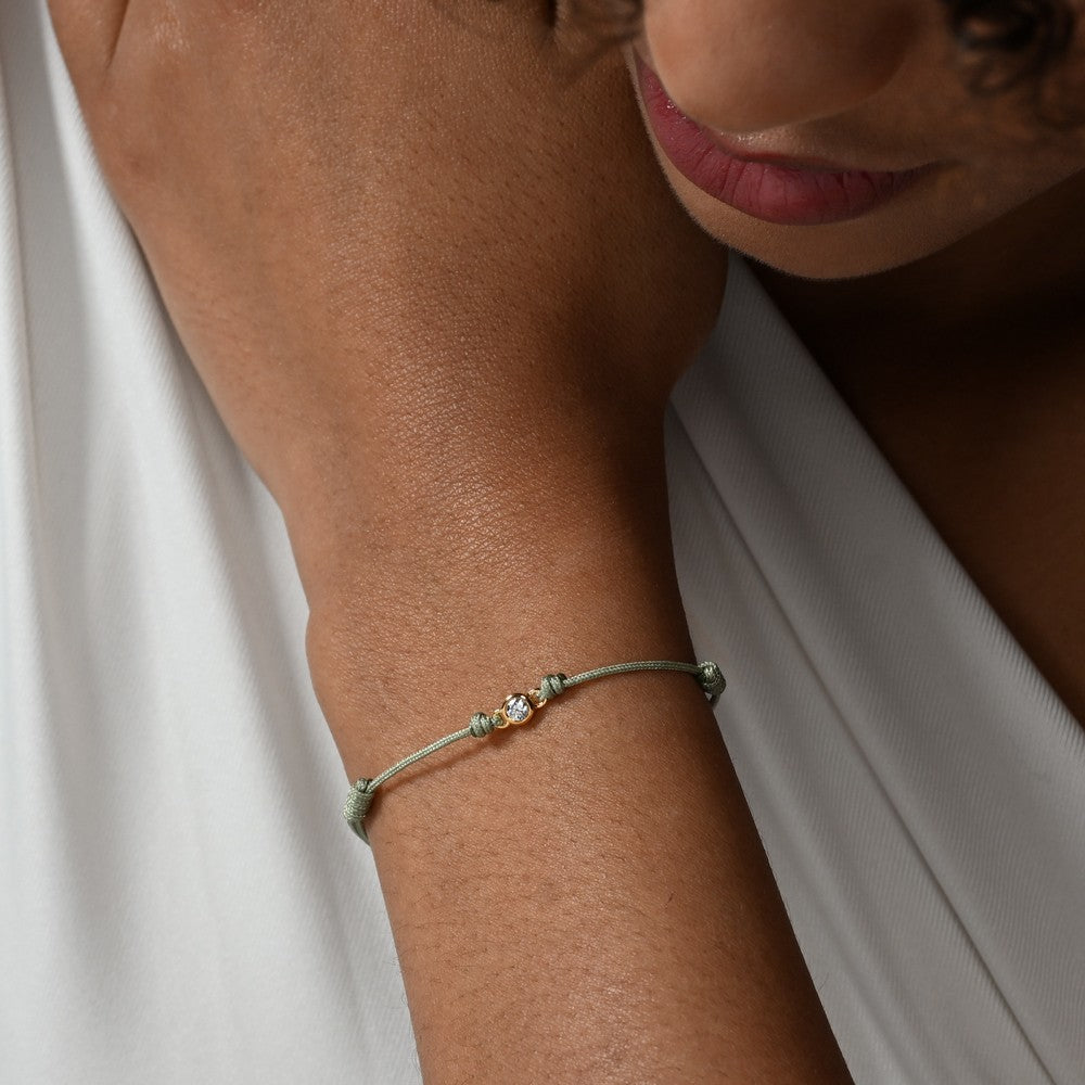 Nahaufnahme von einem grünen Cord-Armband mit einem Labordiamanten im Brillantschliff am Arm getragen.