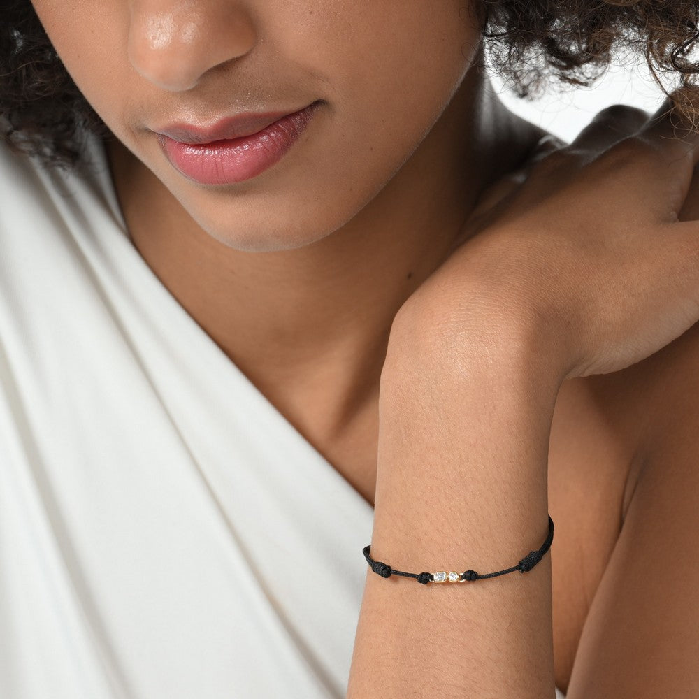 Nahaufnahme von einem schwarzen Cord-Armband mit 2 Labordiamanten im Brillant- und Smaragdschliff am Arm getragen.