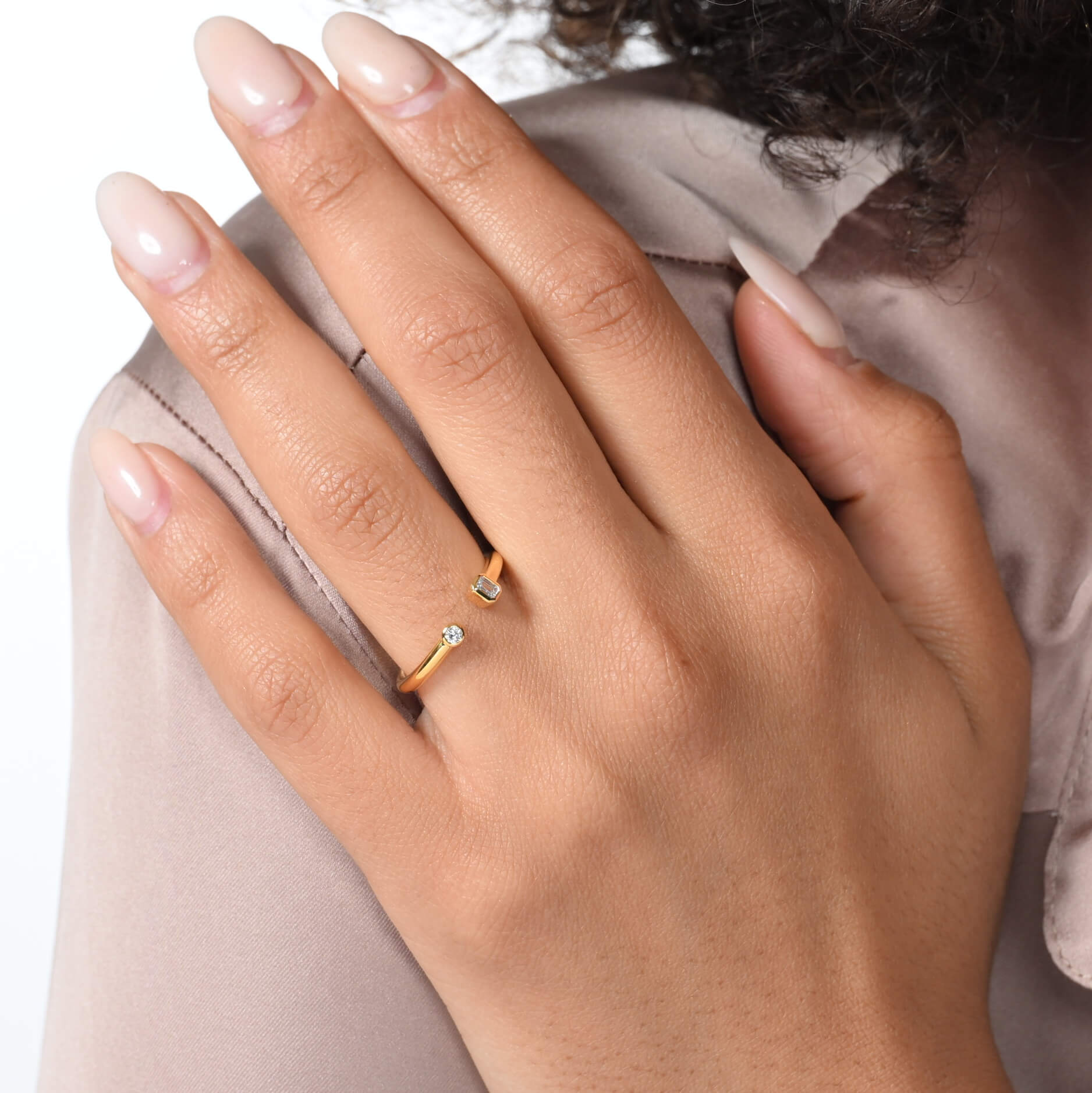 Nahaufnahme von einem vergoldeten Ring mit zwei Labordiamanten im Smaragd- und im Brilliantschliff am Ringfinger getragen.