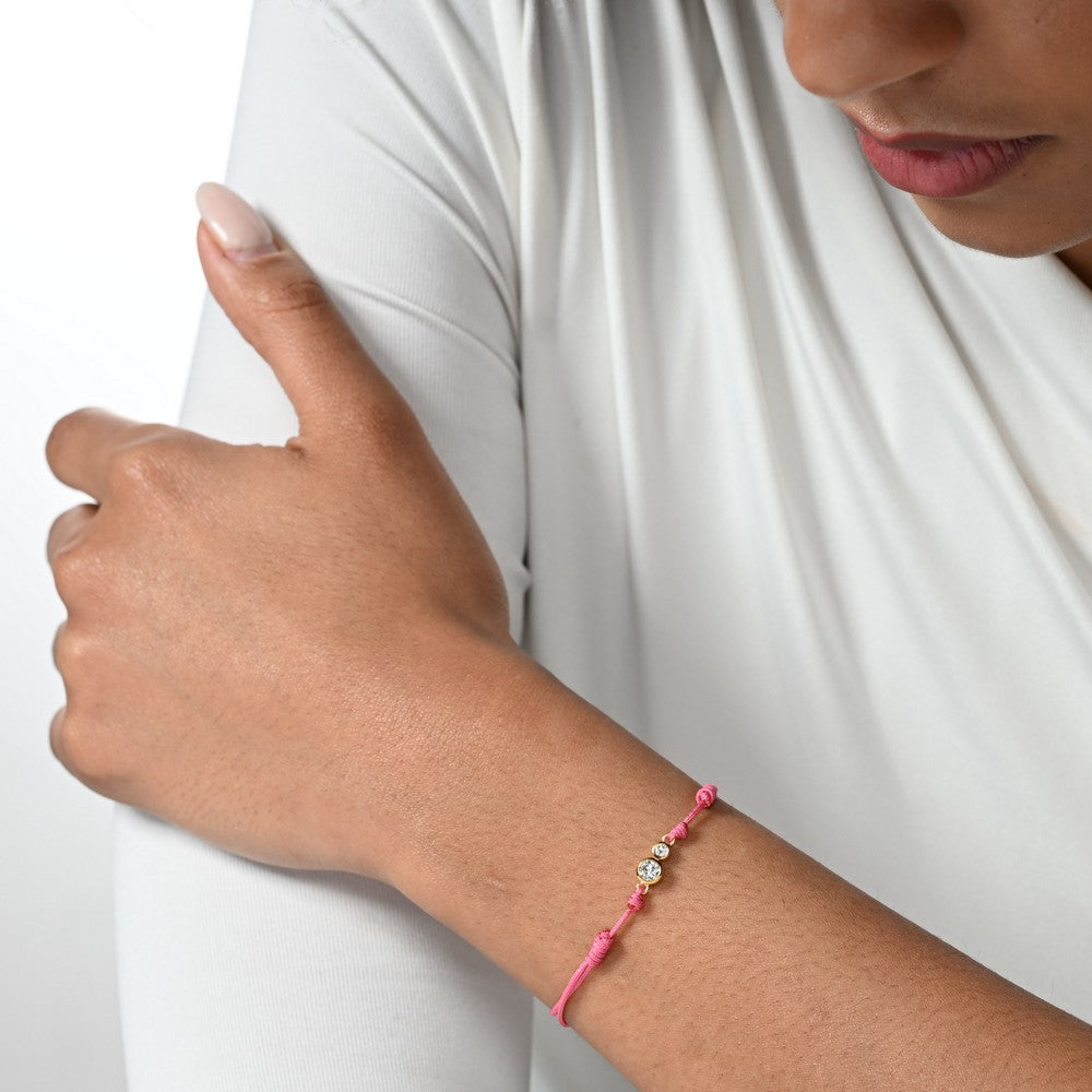 Nahaufnahme von einem pinken Cord-Armband mit zwei Labordiamanten im Brillantschliff am Arm getragen.