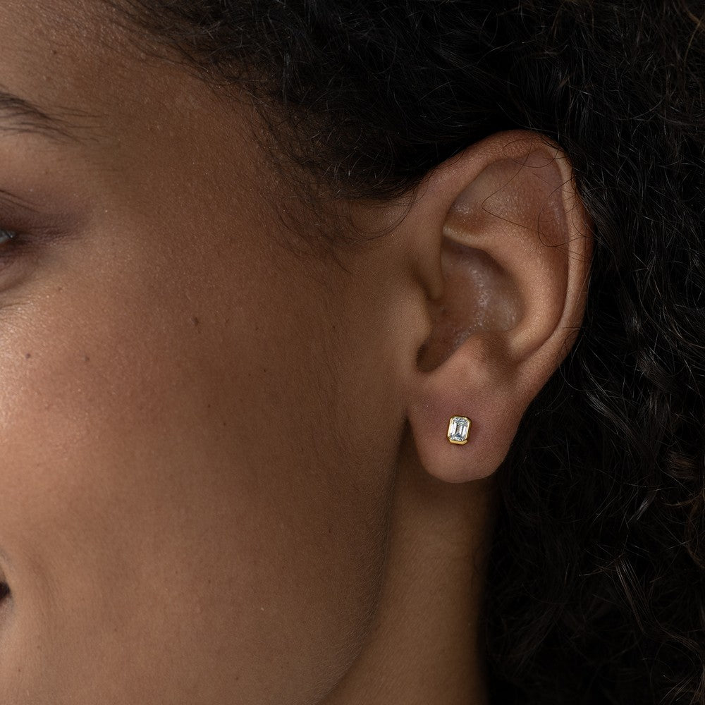 Nahaufnahme von einem einzelnen Diamant-Ohrstecker besetzt mit einem Labordiamanten im Smaragdschliff getragen im Ohr.