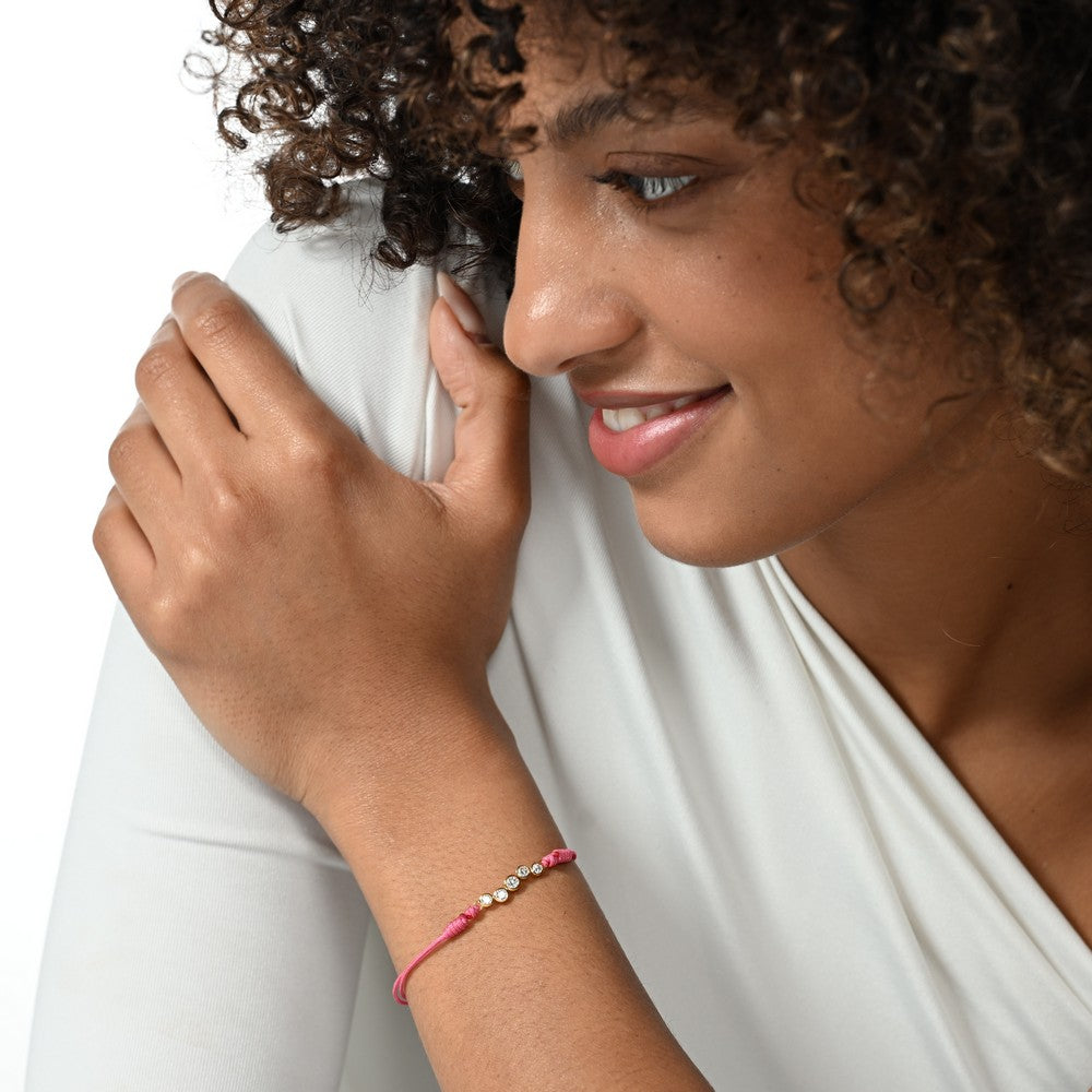 Nahaufnahme von einem pinken Cord-Armband mit fünf runden Labordiamanten im Brillantschliff am Arm getragen.