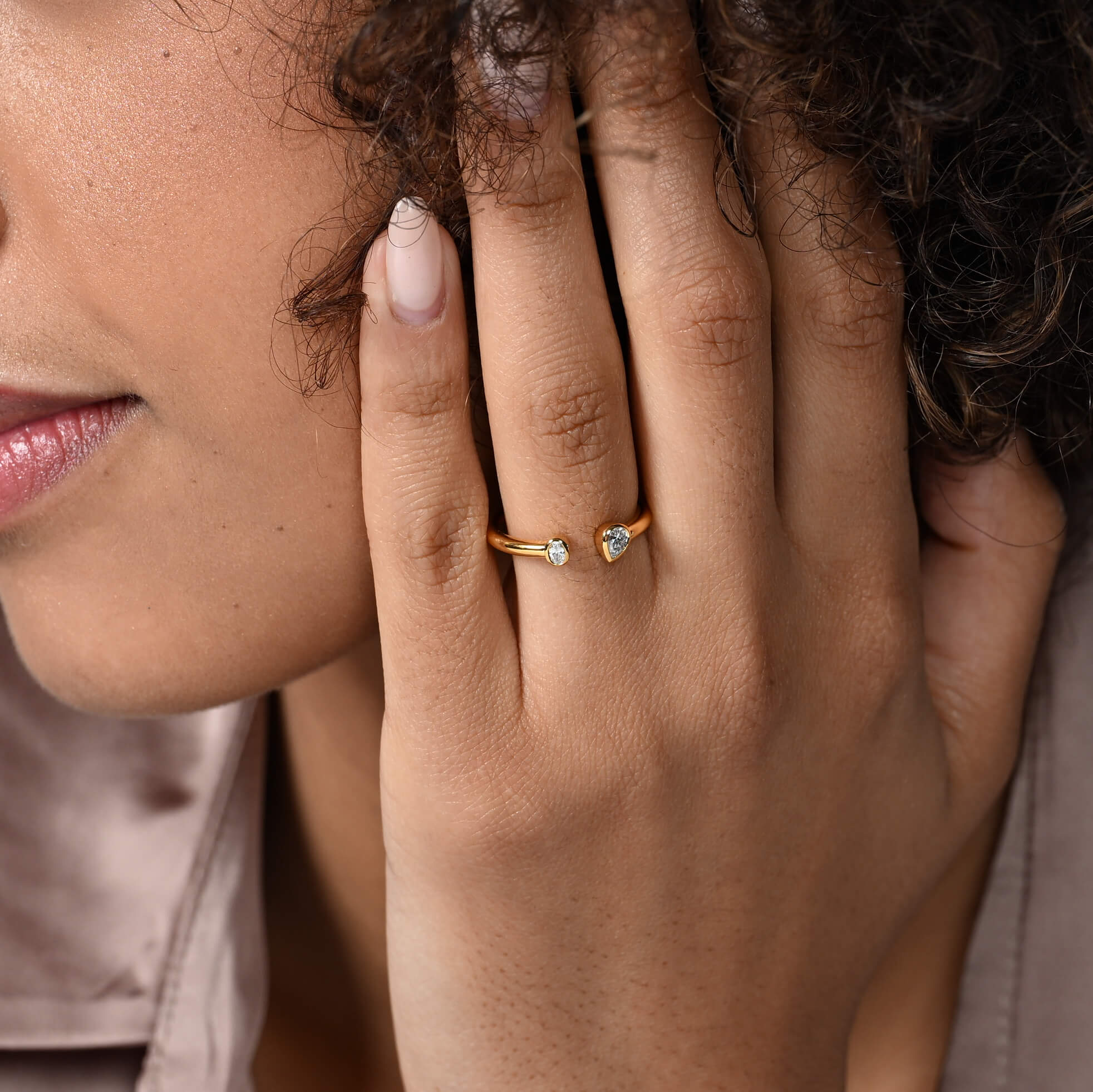 Nahaufnahme von einem vergoldeten Ring mit zwei Labordiamanten im Tropfenschliff und im Ovalschliff am Ringfinger getragen.