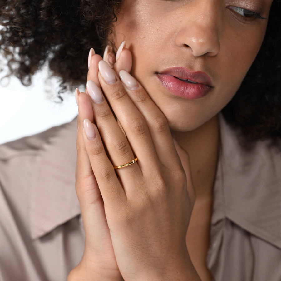Frau trägt einen zierlichen vergoldeten Ring mit einem runden Labordiamanten im Brillantschliff am Ringfinger.