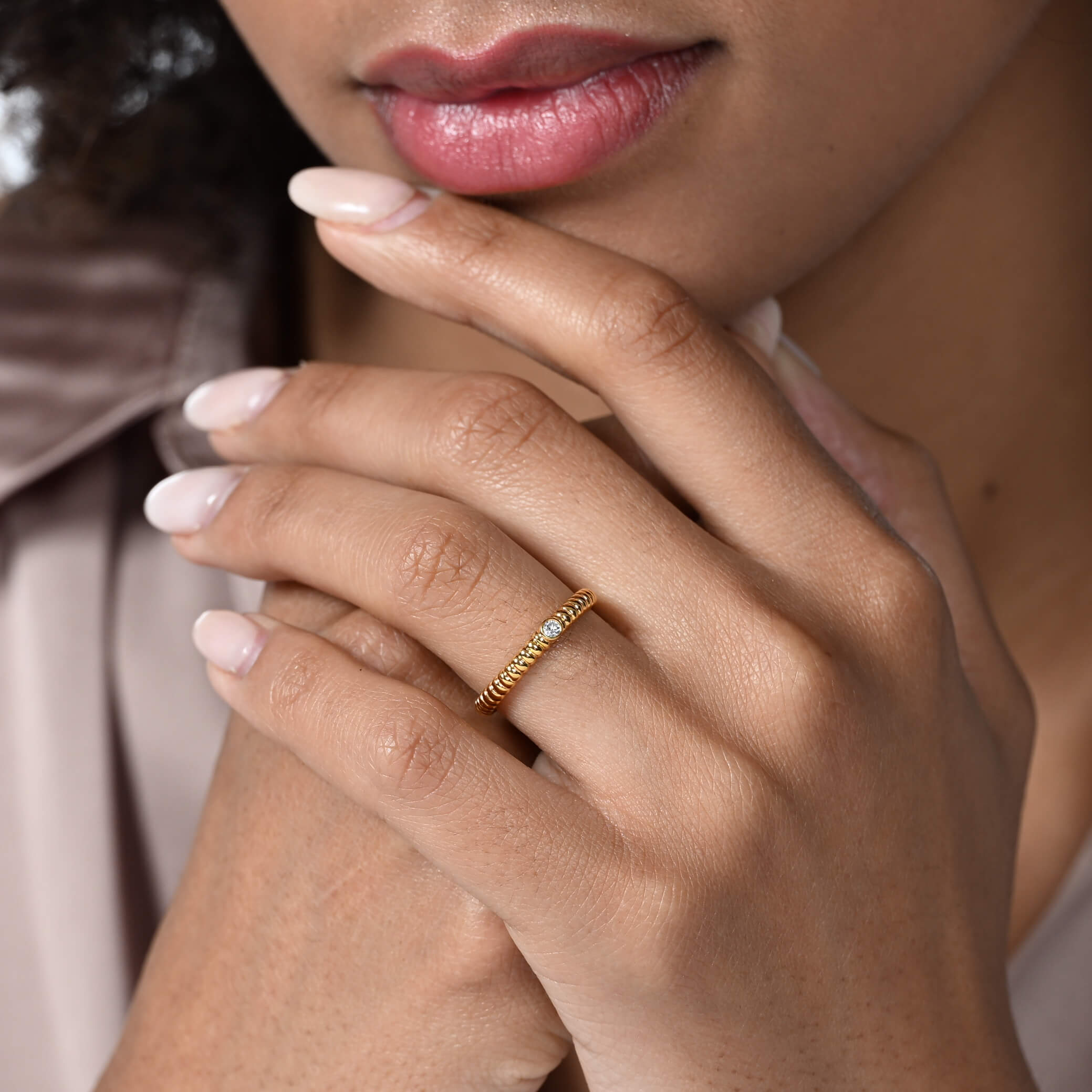 Nahaufnahme von einem vergoldeten Verlobungsring im rope Design mit einem runden Labordiamanten im Brillantschliff am Ringfinger getragen.