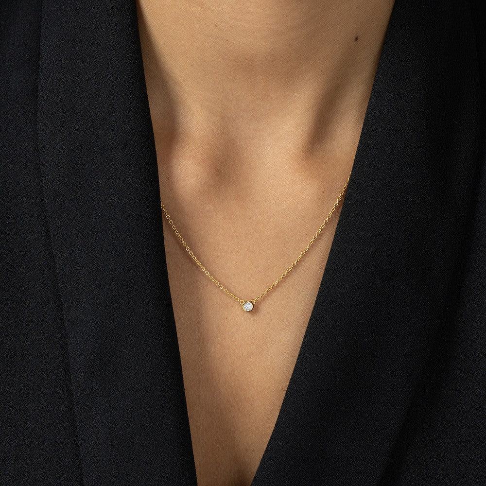 Nahaufnahme von einer goldenen Halskette mit einem kleinen Labordiamanten im runden Brillantschliff getragen am Hals.