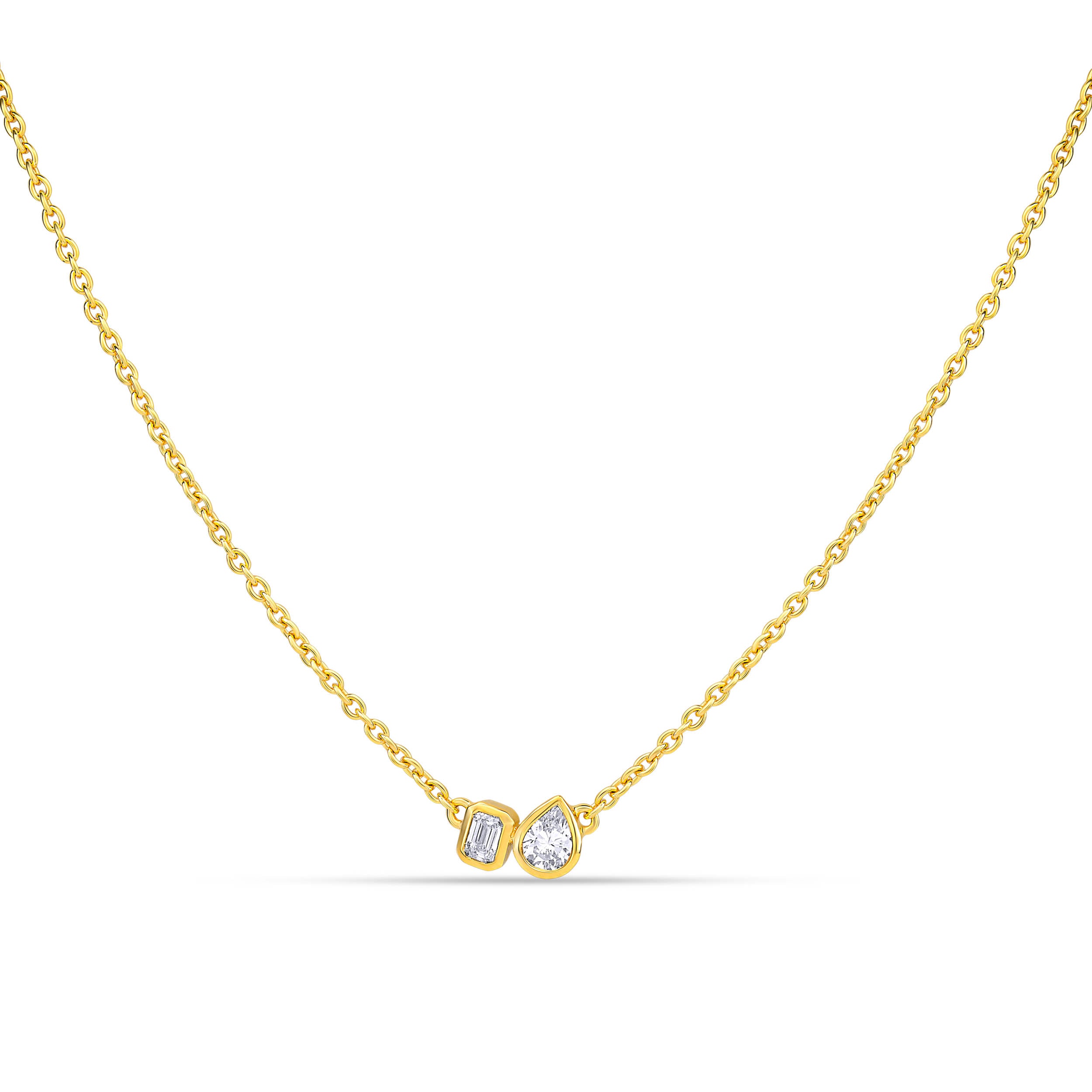 Ein goldene Halskette besetzt mit 2 kleinen Labordiamanten im Tropfen- und im Smaragdschliff auf weißem Hintergrund.