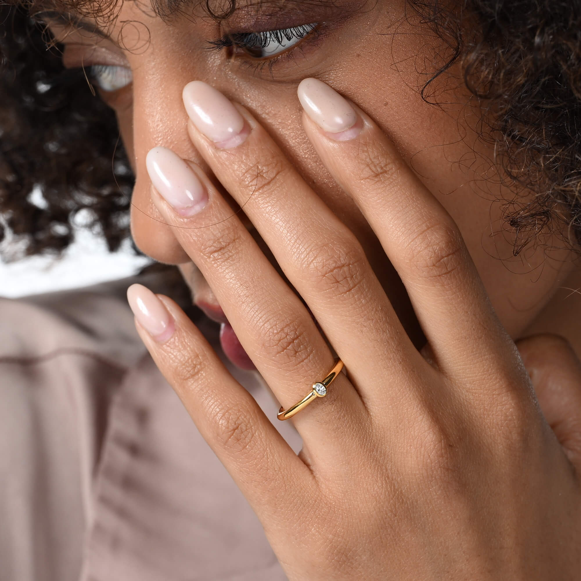 Nahaufnahme von einem vergoldeten Verlobungsring mit einem oval geschliffenen Labordiamanten am Ringfinger getragen.