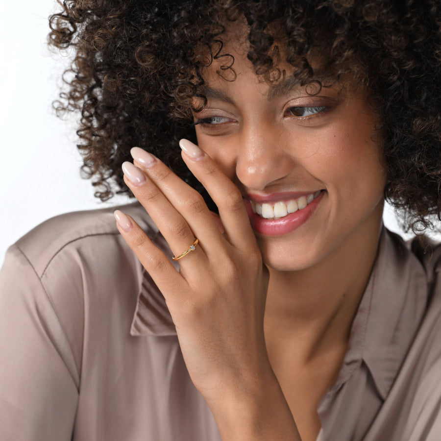 Frau trägt einen einen vergoldeten Verlobungsring mit einem oval geschliffenen Labordiamanten in Zargenfassung am Ringfinger.