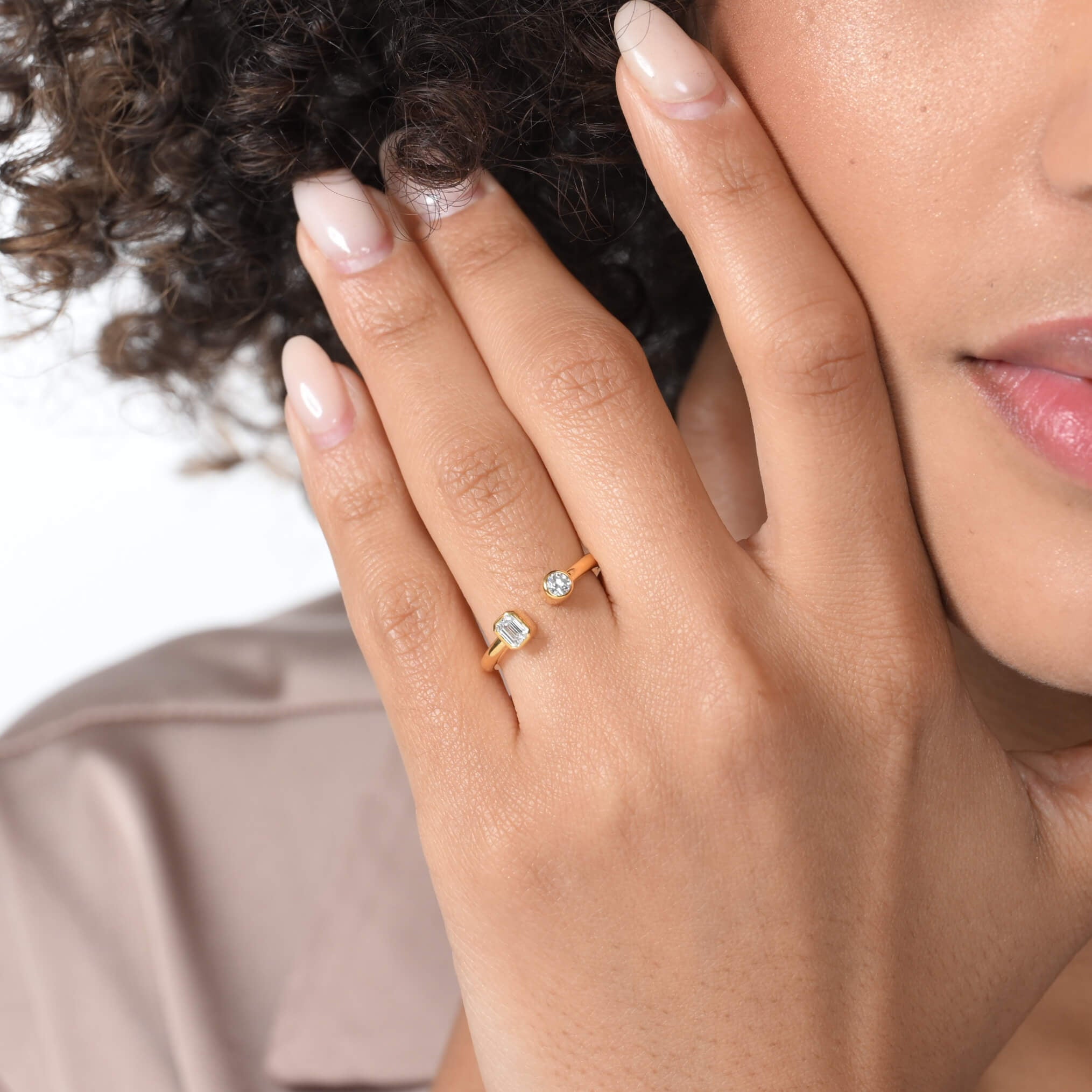 Nahaufnahme von einem vergoldeten Ring mit zwei Labordiamanten im Smaragd- und im Brilliantschliff am Ringfinger getragen.