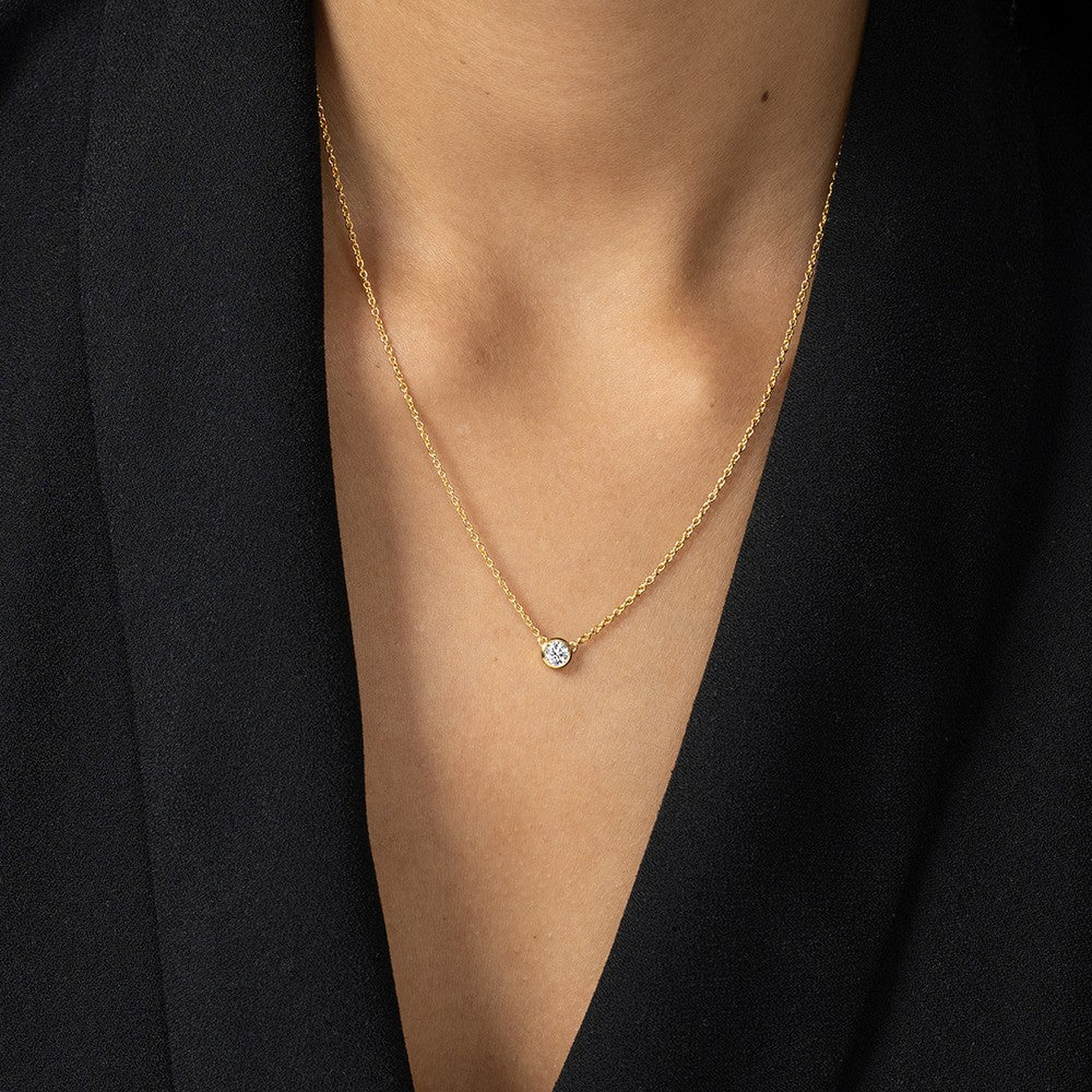 Nahaufnahme von einer goldenen Halskette mit einem Labordiamanten im runden Brillantschliff getragen am Hals.