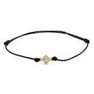 Ein schwarzes Cord-Armband mit einem Labordiamanten im Princessschliff  in Zargenfassung auf weißem Hintergrund