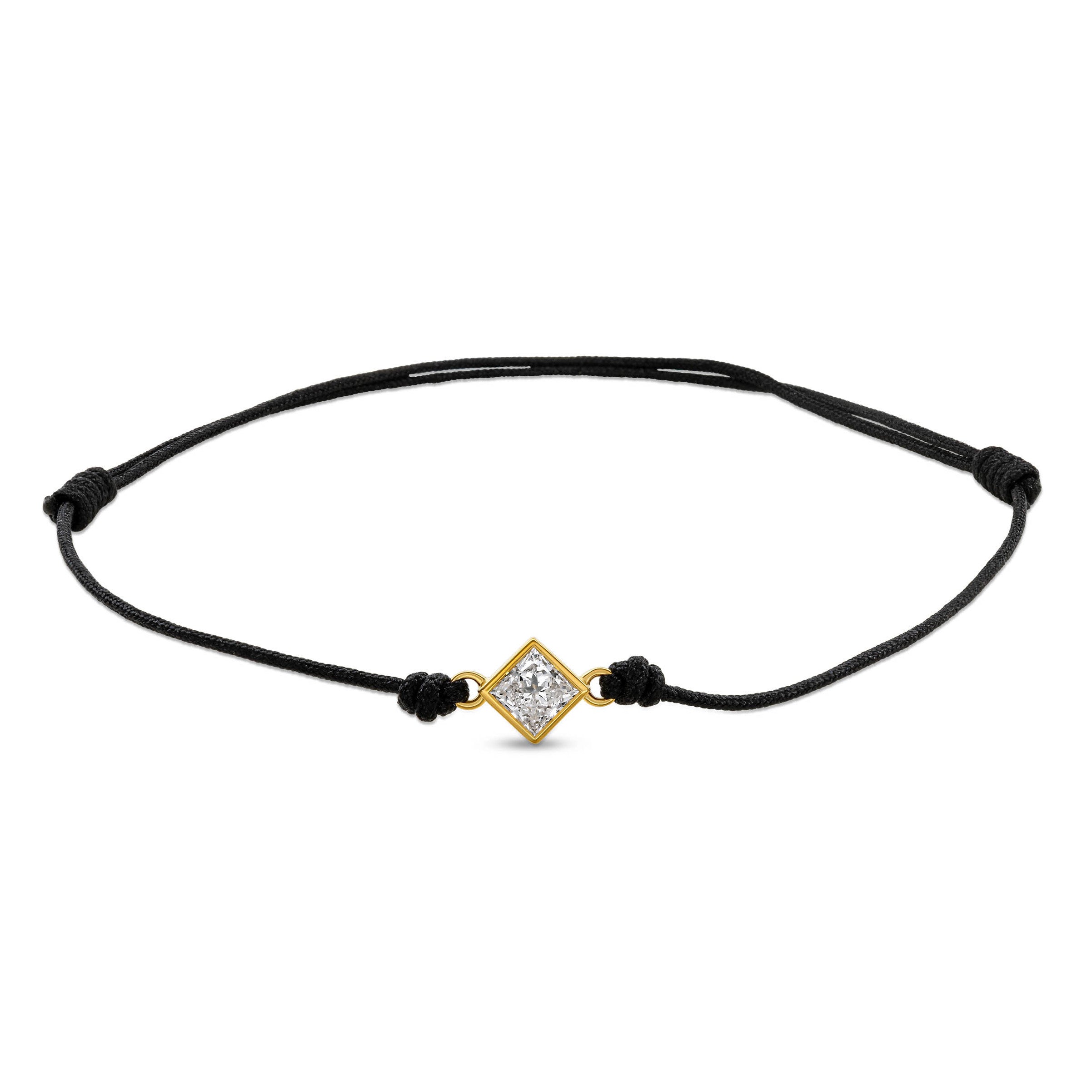 Ein schwarzes Cord-Armband mit einem Labordiamanten im Princessschliff  in Zargenfassung auf weißem Hintergrund