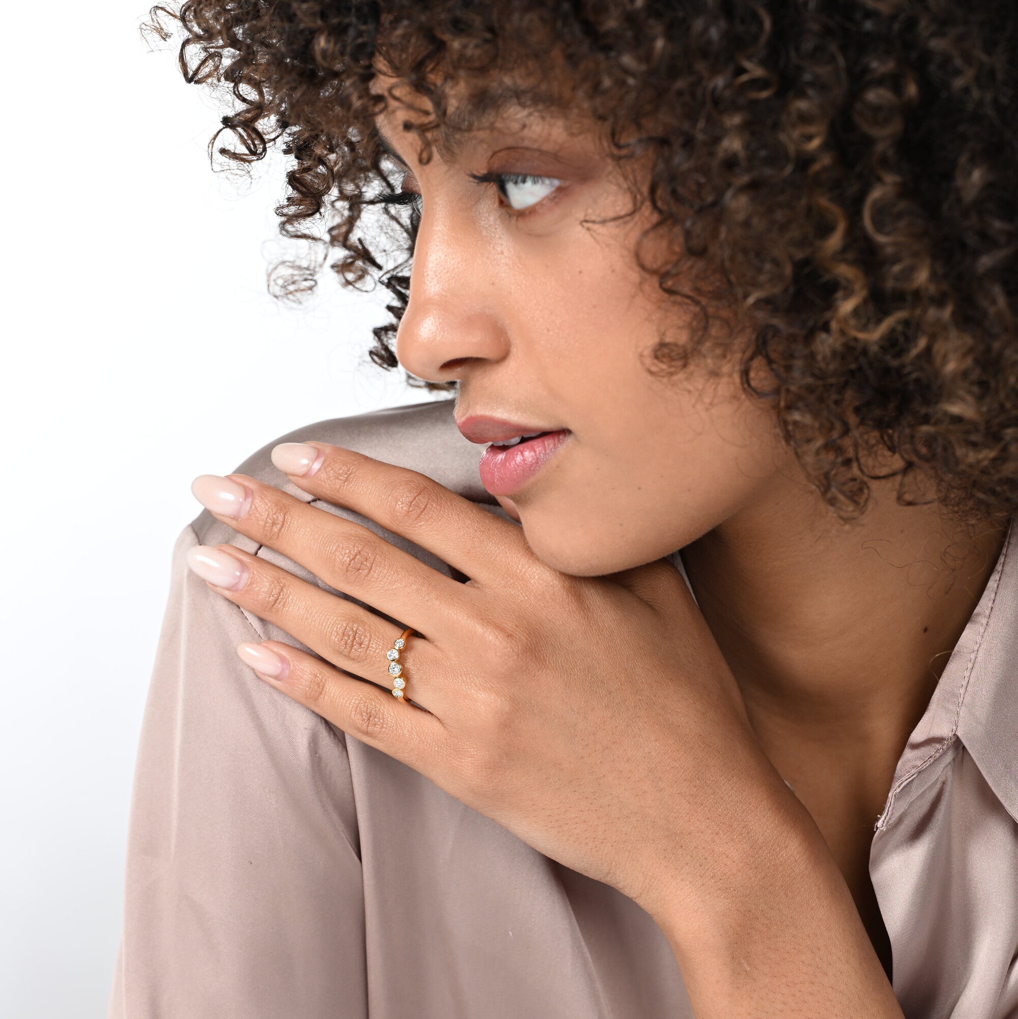 Frau trägt einen vergoldeten Labordiamantring mit 5 Steinen in Zargenfassung am Ringfinger.  