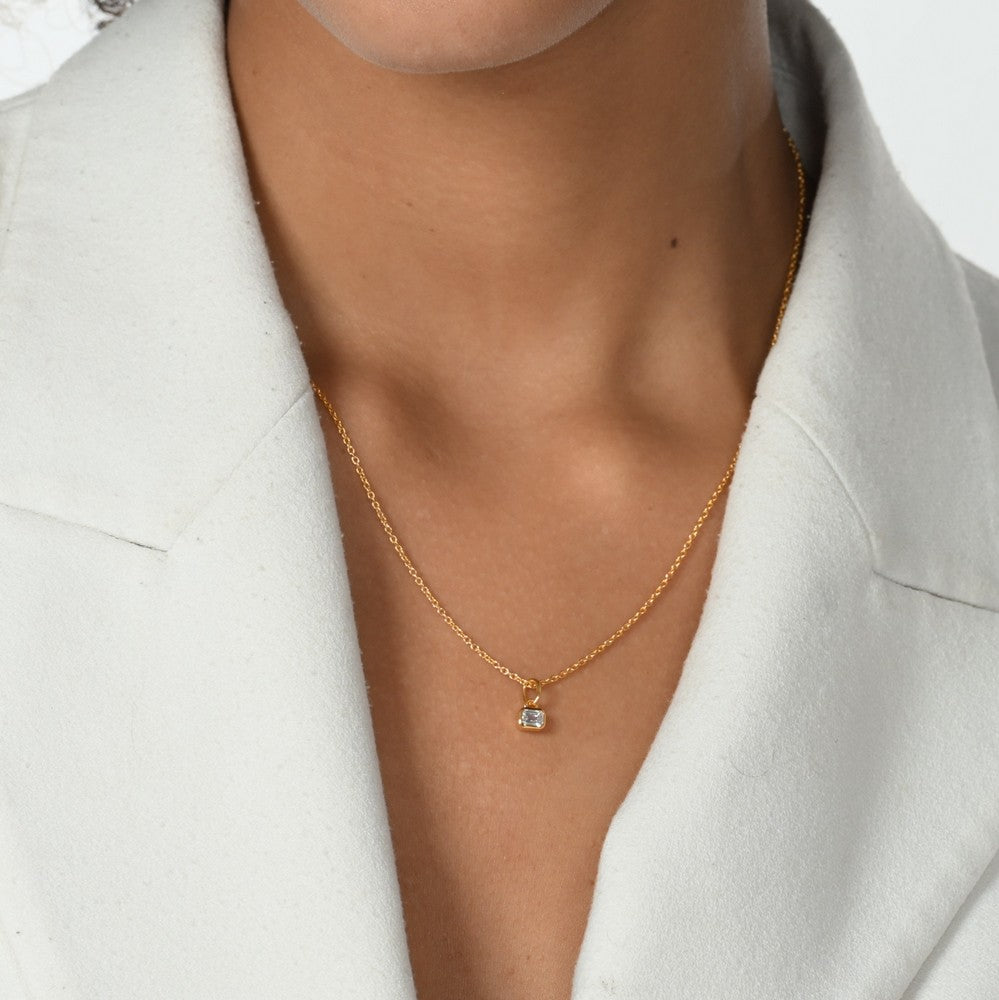 Frau im weißen Blazer trägt eine Halskette mit einem goldenen Anhänger mit Labordiamanten in Oktagonform.