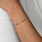 Nahaufnahme von einem grünen Cord-Armband mit einem kleinen Labordiamanten im Princessschliff am Arm getragen.