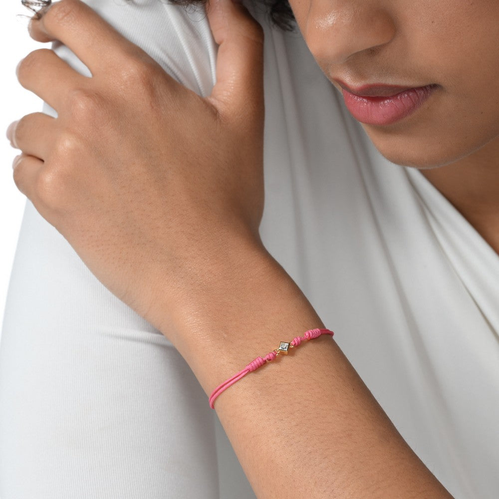 Nahaufnahme von einem pinken Cord-Armband mit einem kleinen Labordiamanten im Princessschliff am Arm getragen.