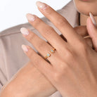 Nahaufnahme von einem vergoldeten Ring mit zwei Labordiamanten im Carree- und im Marquiseschliff am Ringfinger getragen.