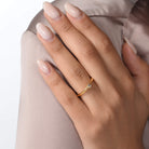 Nahaufnahme von einem vergoldeten Verlobungsring mit einem Labordiamanten im Smaragdschliff am Ringfinger getragen.