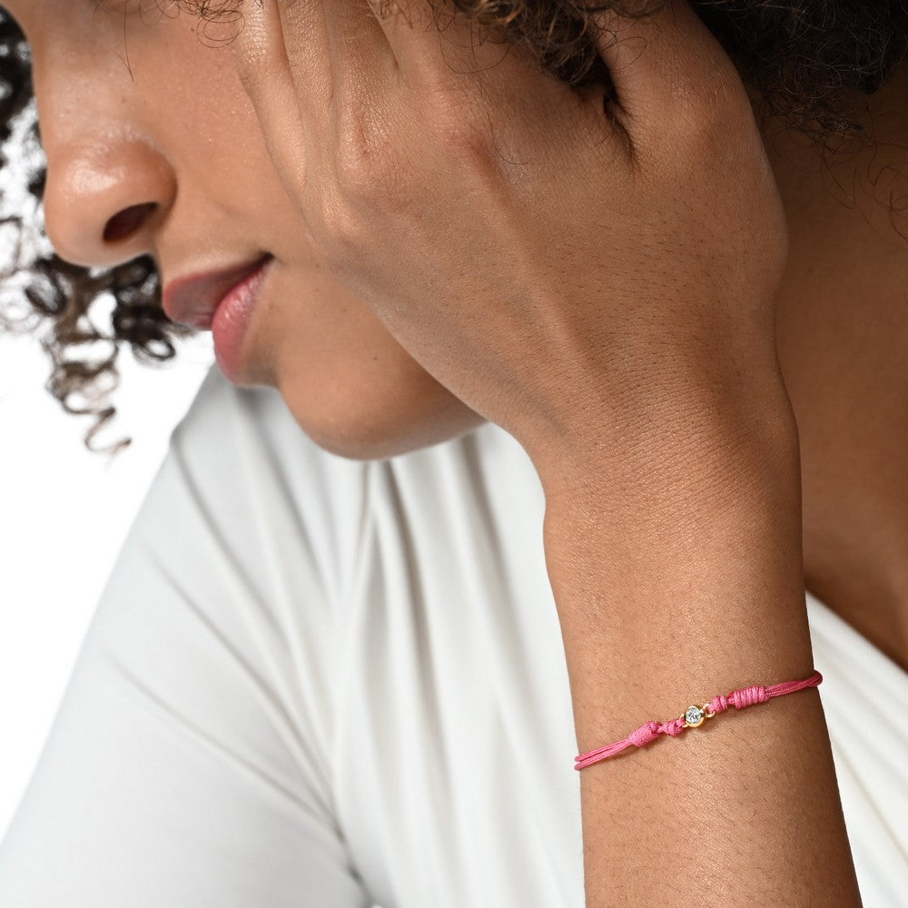 Nahaufnahme von einem pinken Cord-Armband mit einem Labordiamanten im Brillantschliff am Arm.