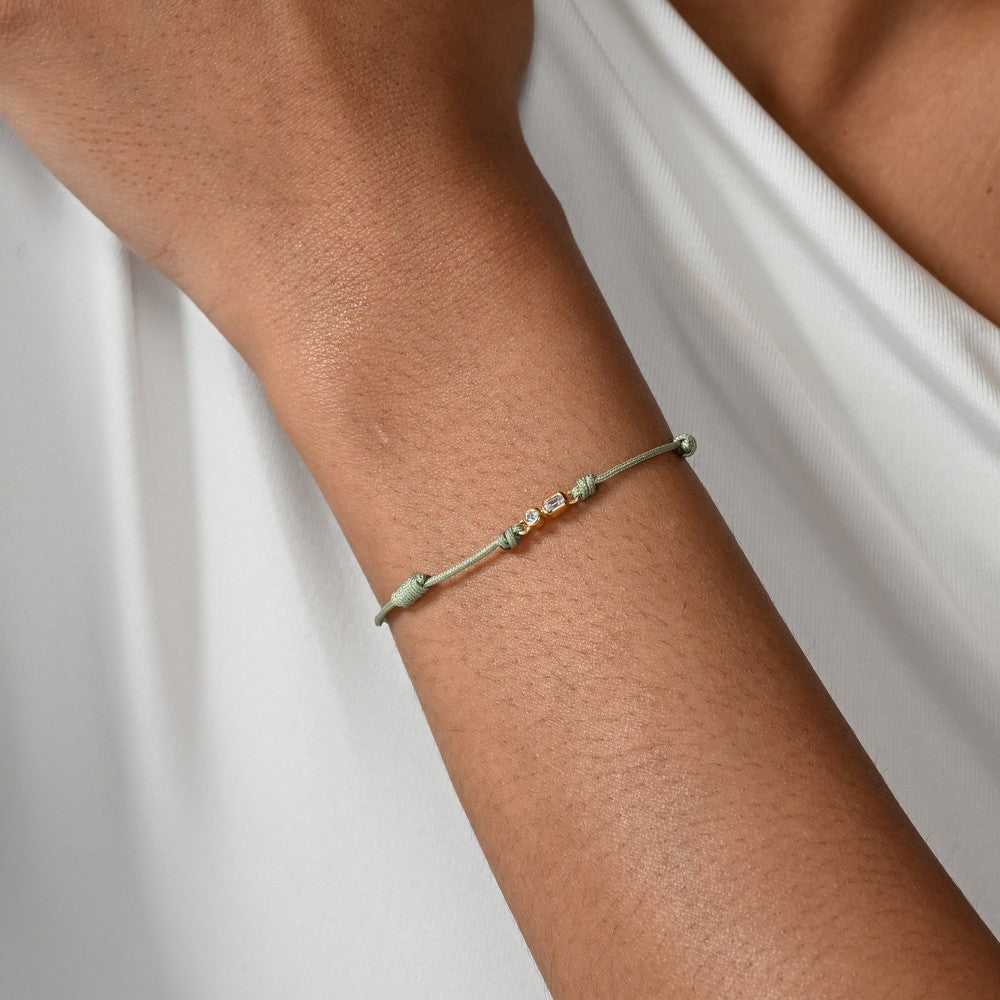 Nahaufnahme von einem grünen Cord-Armband mit 2 Labordiamanten im Brillant- und Smaragdschliff am Arm getragen.