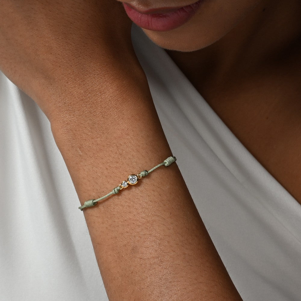 Nahaufnahme von einem grünen Cord-Armband mit zwei Labordiamanten im Brillantschliff am Arm getragen.
