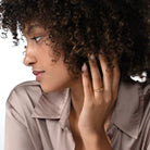 Frau trägt einen vergoldeten Ring mit zwei Labordiamanten im Tropfenschliff und im Ovalschliff in Zargenfassung am Ringfinger.  