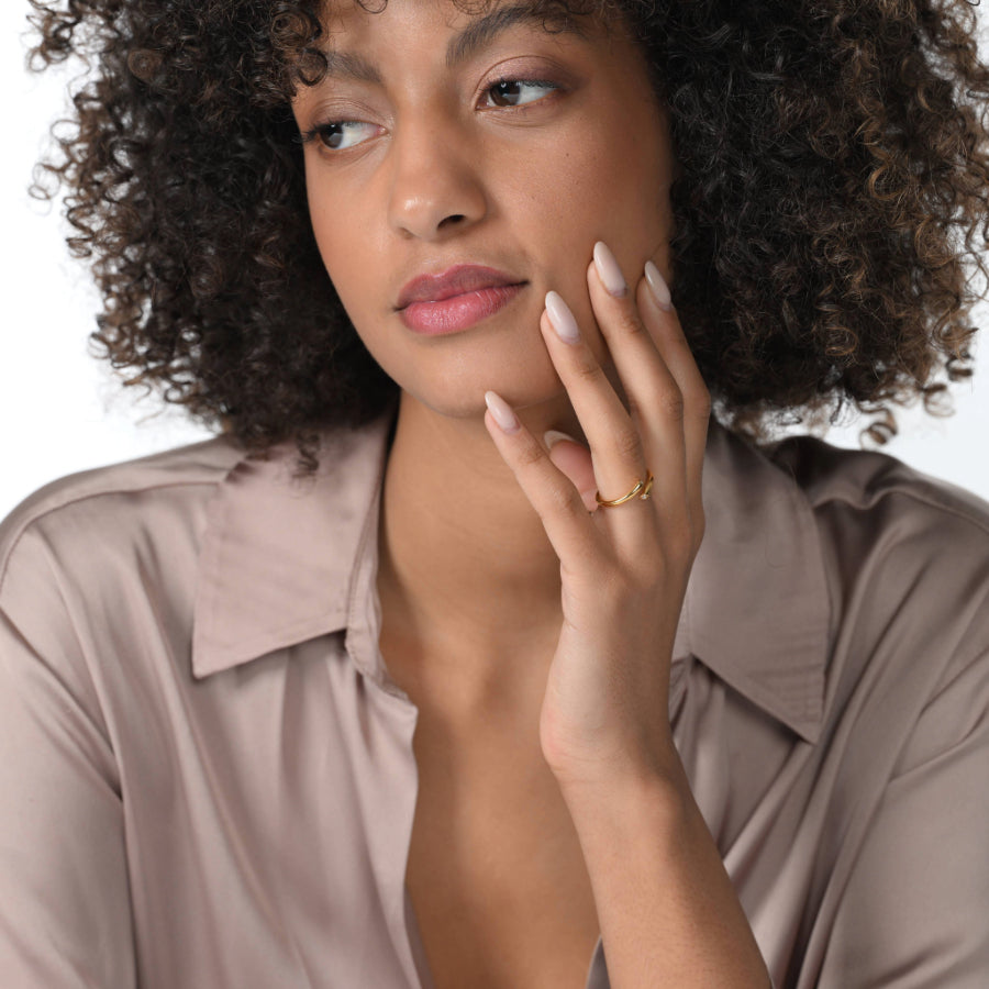 Frau trägt einen einen vergoldeten Ring im offenen Design mit zwei runden Labordiamanten im Brillantschliff  am Ringfinger.  