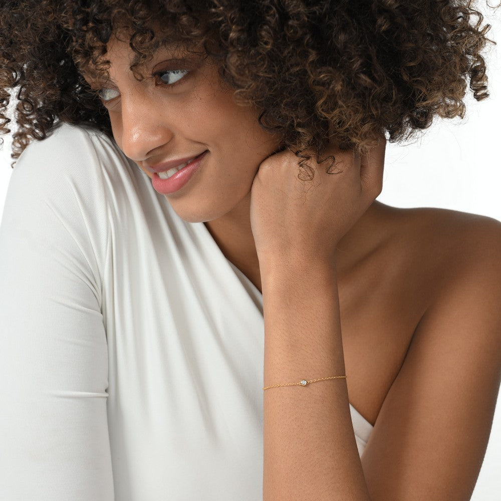 Frau trägt eine vergoldete Armkette mit einem einzelnen runden Labordiamanten im Brillantschliff.