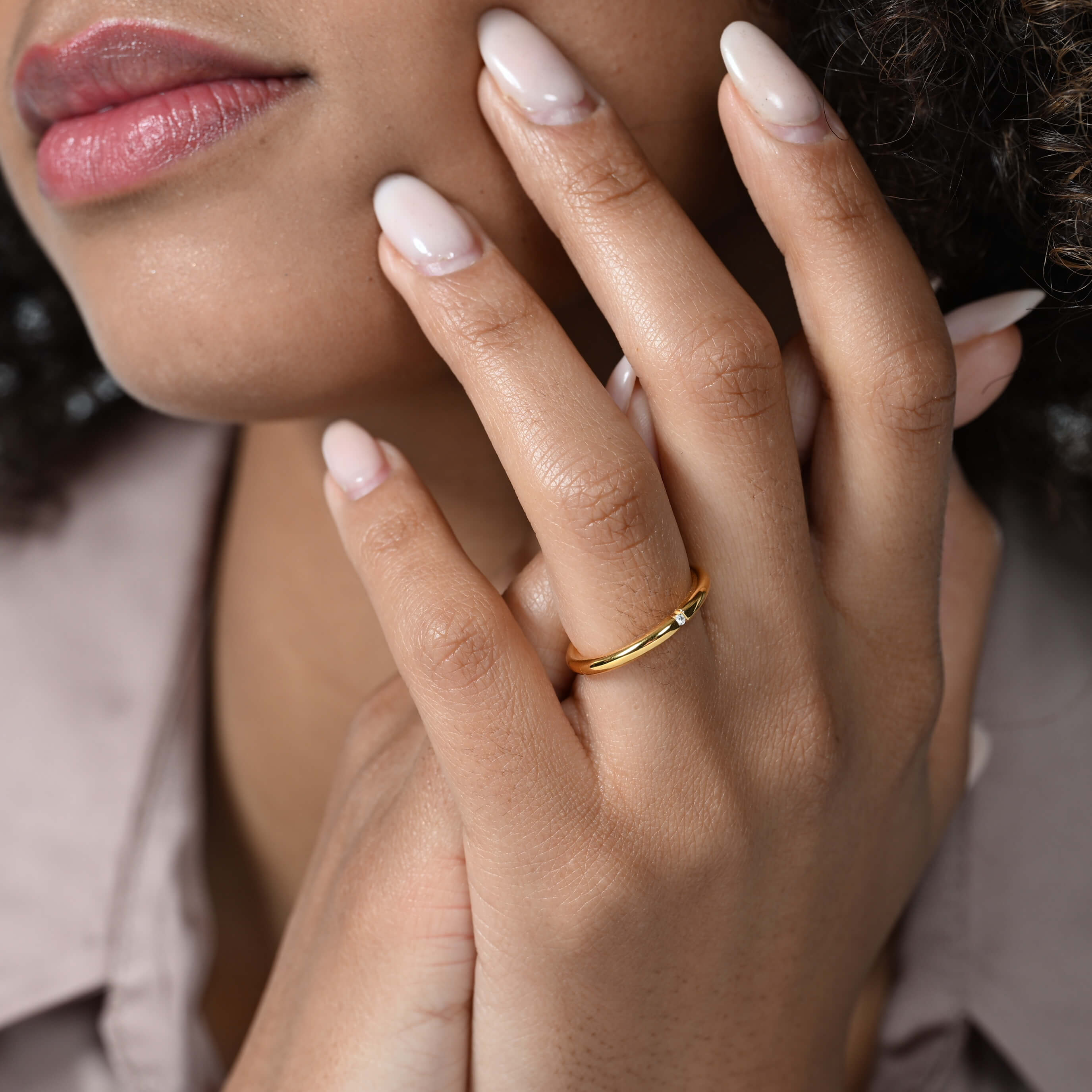 Nahaufnahme von einem zierlichen vergoldeten Ring mit einem runden Labordiamanten im Brillantschliff am Ringfinger getragen.