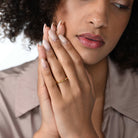 Frau trägt einen zierlichen vergoldeten Ring mit einem runden Labordiamanten im Brillantschliff am Ringfinger.  