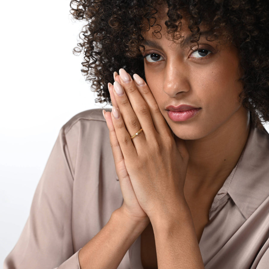 Frau trägt einen einen vergoldeten Verlobungsring im rope Design mit einem runden Labordiamanten im Brillantschliff in Zargenfassung am Ringfinger.  