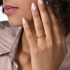 Nahaufnahme von einem zierlichen vergoldeten Ring mit sieben runden Labordiamanten im Brillantschliff am Ringfinger getragen.