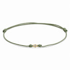 Detailansicht von einem grünen Cord-Armband mit einem kleinen Labordiamanten im Brillantschliff  in Zargenfassung auf weißem Hintergrund.