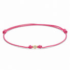 Detailansicht von einem pinken Cord-Armband mit einem kleinen Labordiamanten im Brillantschliff  in Zargenfassung auf weißem Hintergrund.