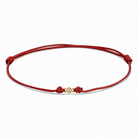 Detailansicht von einem roten Cord-Armband mit einem kleinen Labordiamanten im Brillantschliff  in Zargenfassung auf weißem Hintergrund.
