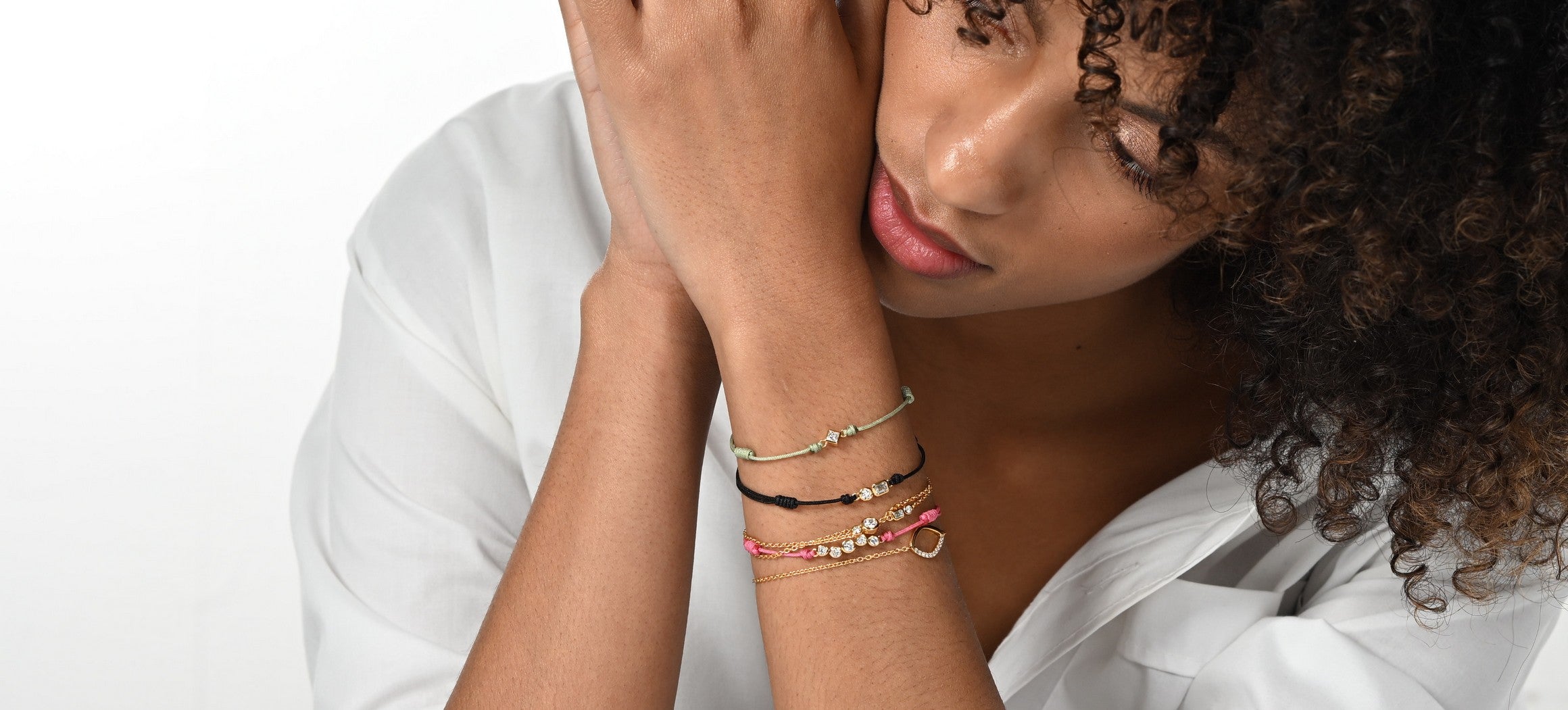 Model trägt einen Stack aus Lab-Grown-Diamant Cord-Armbändern in verschiedenen Farben aus 18 Karat vergoldetem Sterlingsilber.