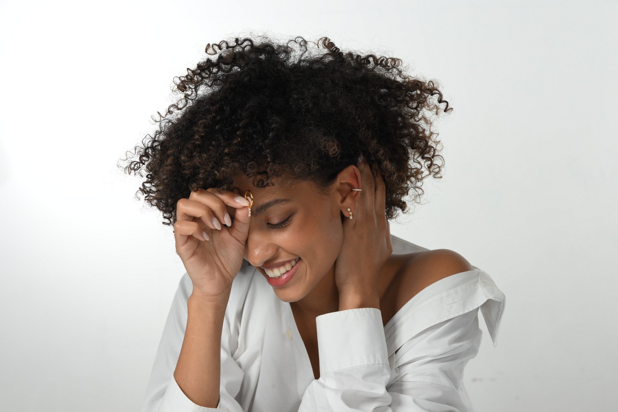 Lächelndes Model trägt Lab-Grown-Diamant Ohrringe und einen Ear Cuff aus 18 Karat vergoldetem Sterlingsilber.